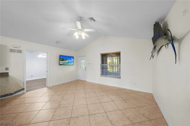 a view of an empty room with window and chandelier fan