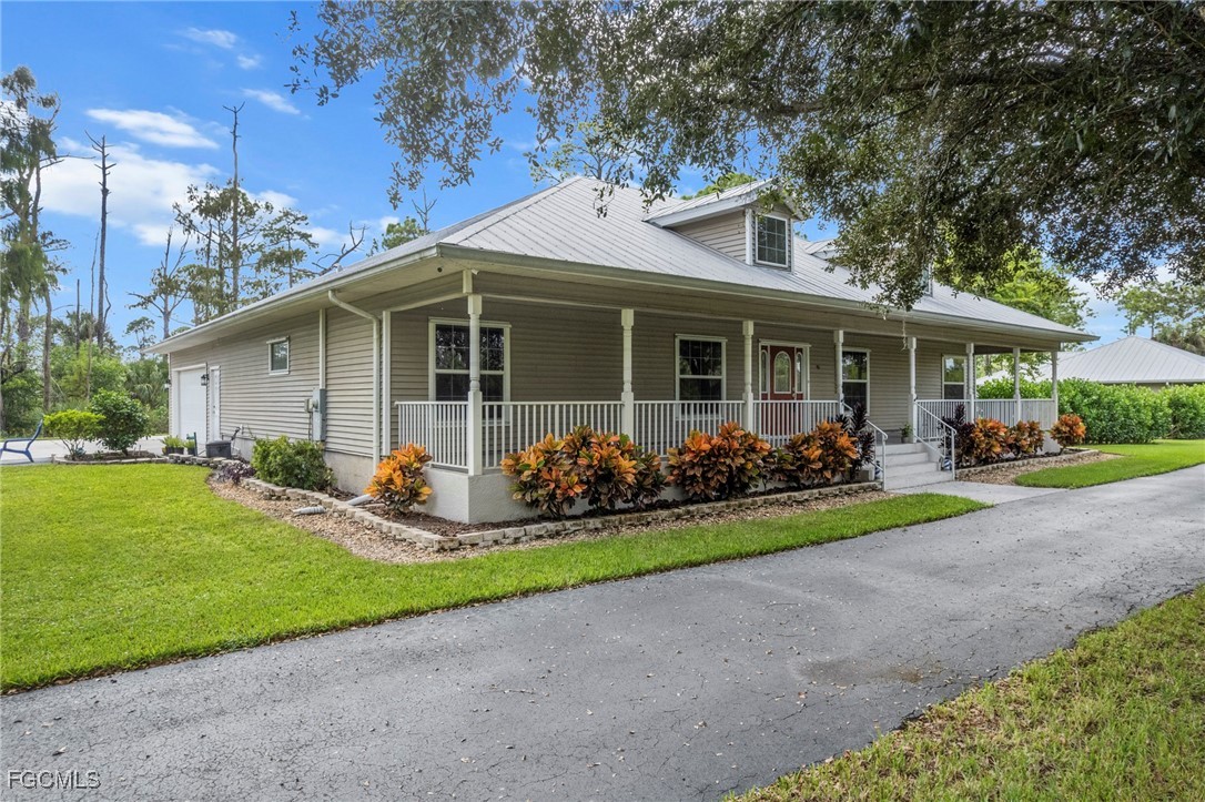 90 24th Avenue Northeast Naples, FL 34120 - Photo 3 of 44 a front view of a house with a garden and yard