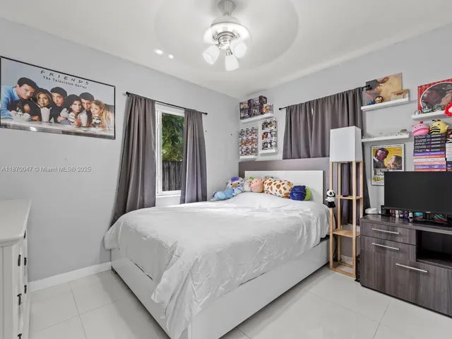 a bedroom with a bed a computer on the desk and a window