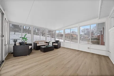 a living room with furniture large windows and wooden floor