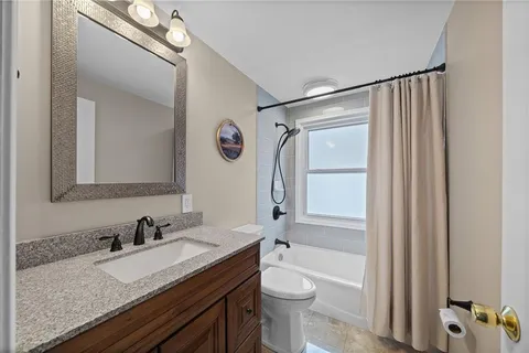 a bathroom with a granite countertop sink mirror vanity and toilet