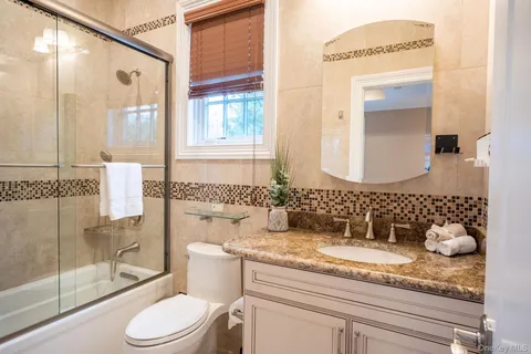 a bathroom with a granite countertop sink toilet and shower