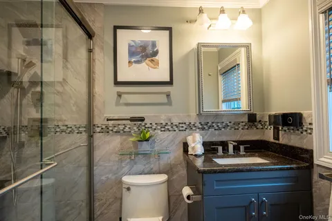 a bathroom with a granite countertop sink and a toilet