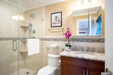 a bathroom with a granite countertop sink a toilet and shower