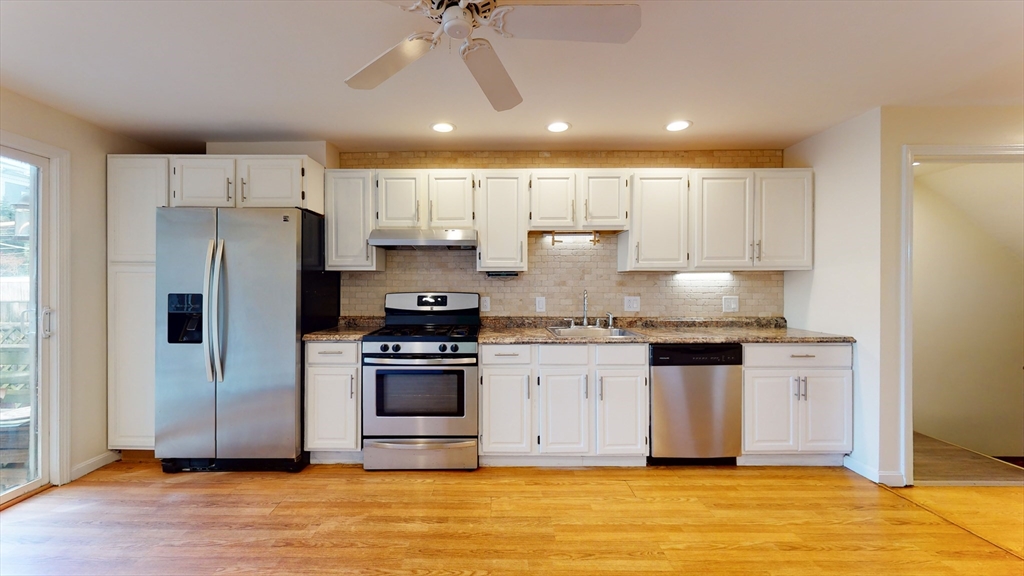 a kitchen with stainless steel appliances a stove a refrigerator sink and white cabinets