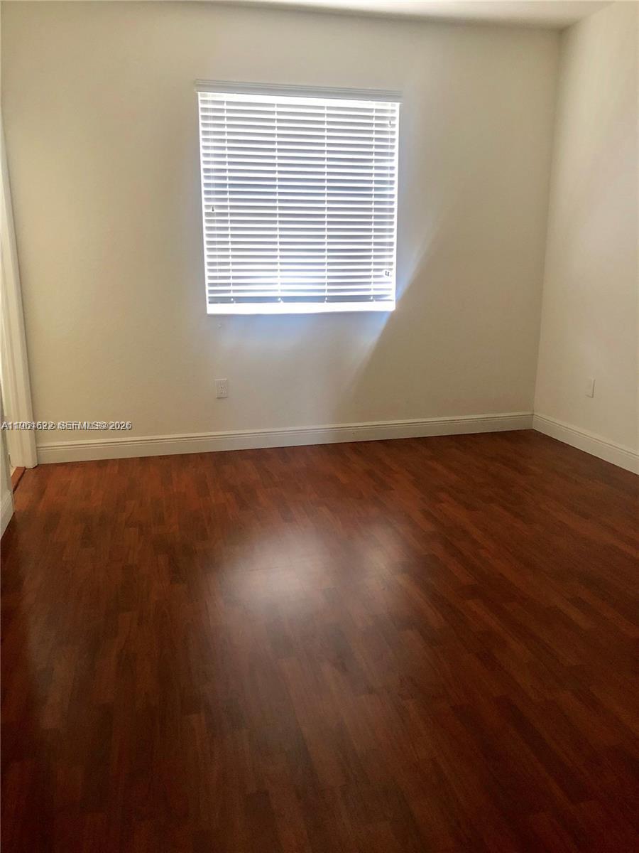 9041 Southwest 227th Street, Unit 5 Cutler Bay, FL 33190 - Photo 11 of 27 an empty room with wooden floor and windows