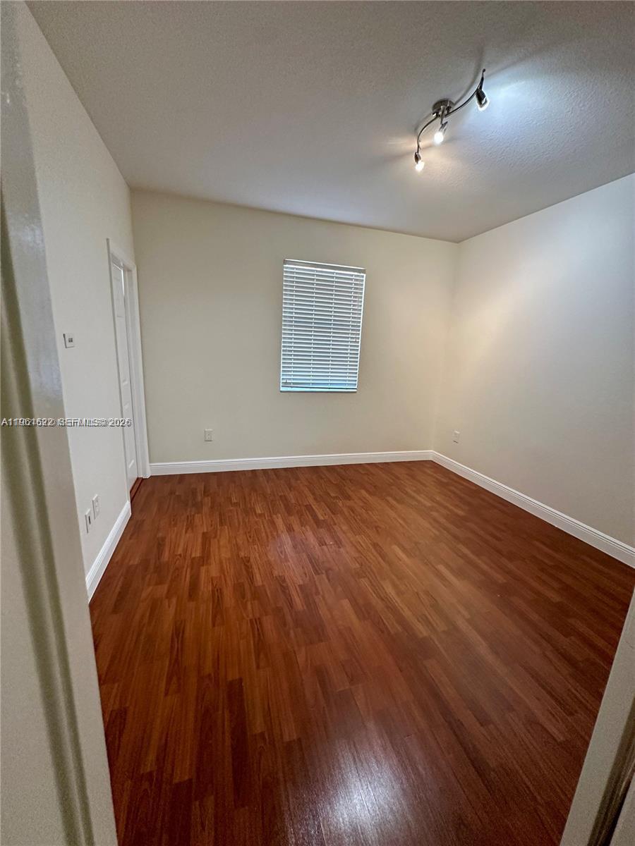 9041 Southwest 227th Street, Unit 5 Cutler Bay, FL 33190 - Photo 16 of 27 an empty room with wooden floor and windows