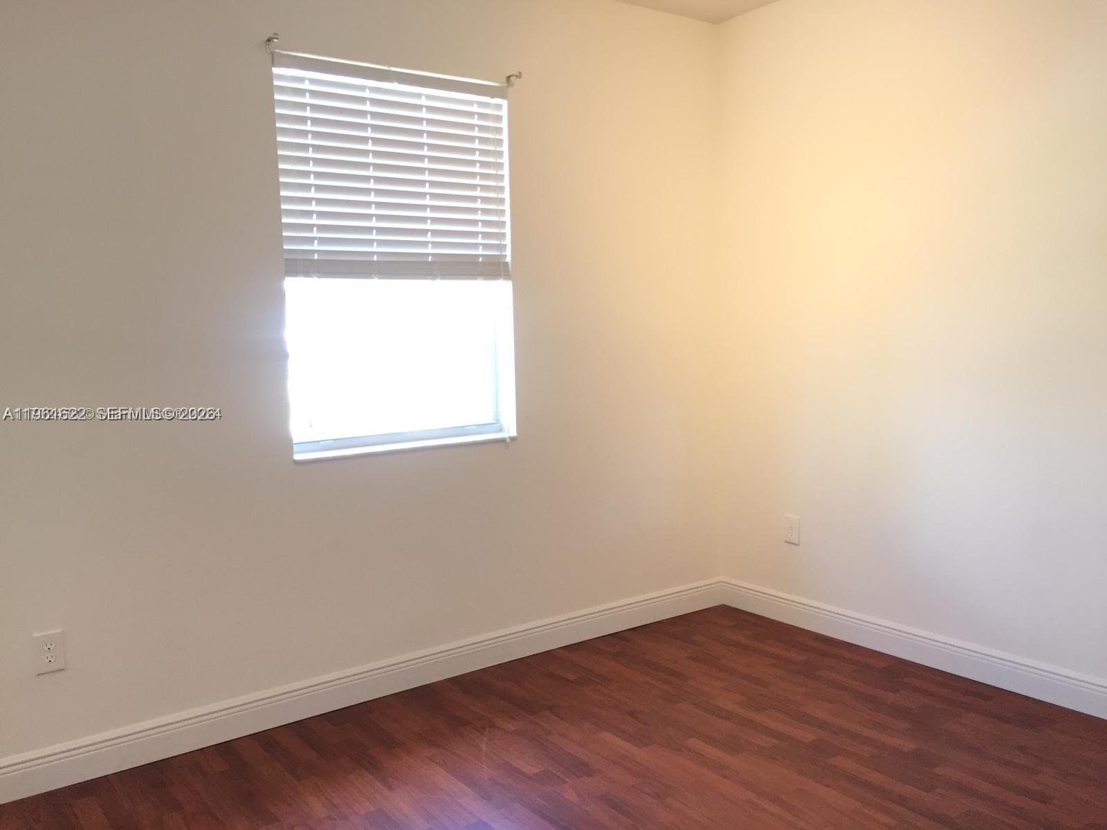 9041 Southwest 227th Street, Unit 5 Cutler Bay, FL 33190 - Photo 17 of 27 an empty room with wooden floor and a window