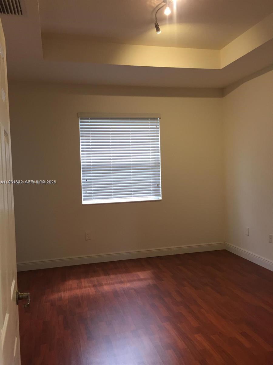 9041 Southwest 227th Street, Unit 5 Cutler Bay, FL 33190 - Photo 18 of 27 an empty room with wooden floor and windows