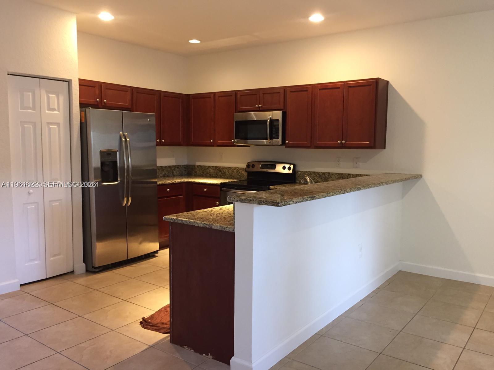 9041 Southwest 227th Street, Unit 5 Cutler Bay, FL 33190 - Photo 5 of 27 a kitchen with stainless steel appliances a refrigerator and a stove top oven