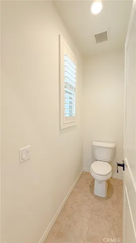 a white toilet sitting in a bathroom next to a window