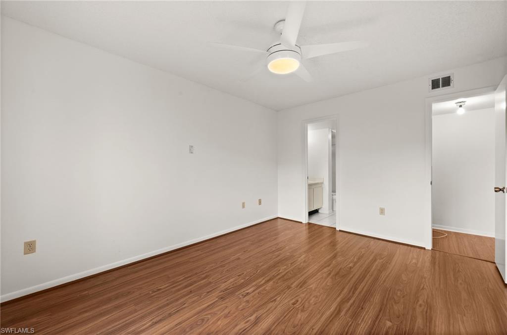 4251 27th Court Southwest, Unit 104 Naples, FL 34116 - Photo 16 of 22 an empty room with wooden floor and mirror