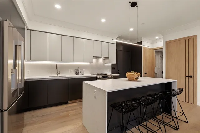 a kitchen with kitchen island granite countertop a sink cabinets and stainless steel appliances