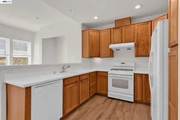 a kitchen with stainless steel appliances granite countertop a sink a stove a refrigerator and island with wooden floor