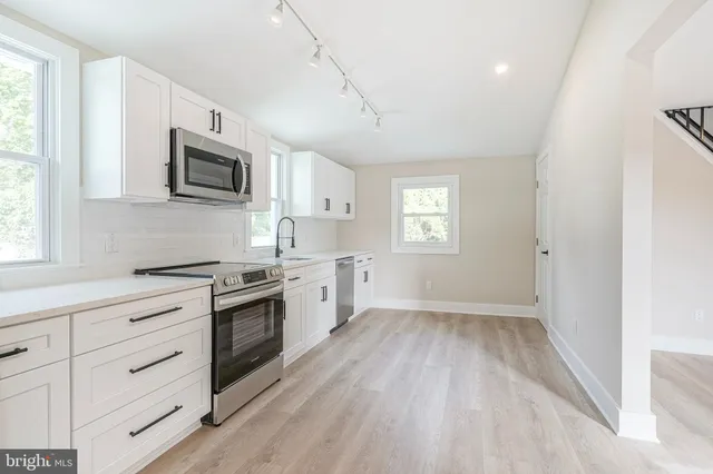 a kitchen with cabinets stainless steel appliances a sink and a window