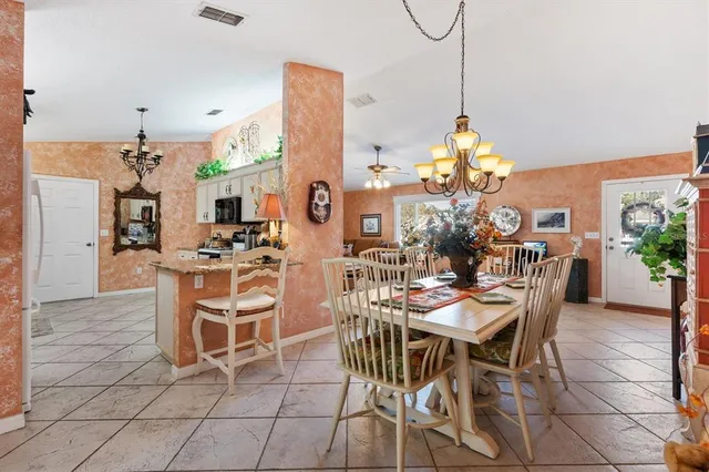 a dining room with furniture a chandelier and kitchen view