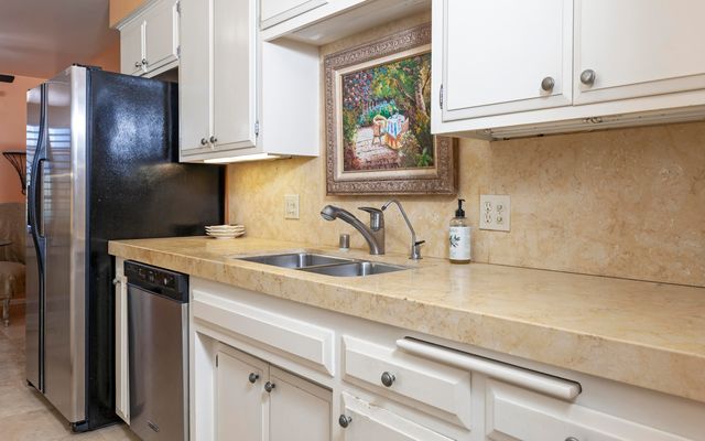 a kitchen with stainless steel appliances granite countertop a sink and a refrigerator