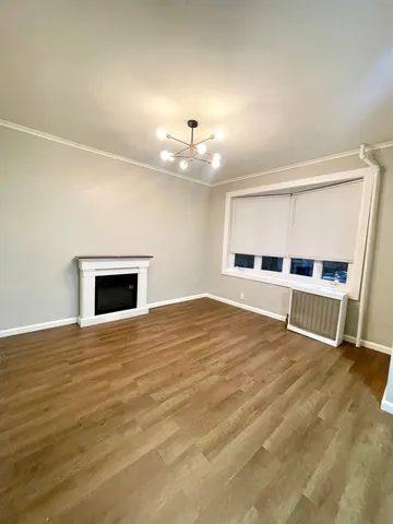 a view of an empty room with wooden floor and a fireplace