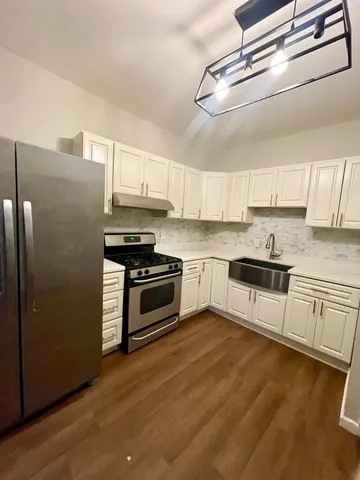 a kitchen with granite countertop a refrigerator stove top oven and sink