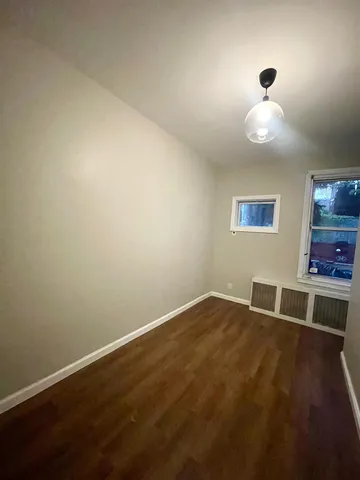 an empty room with wooden floor and window