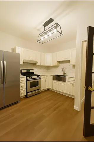 a kitchen with stainless steel appliances a refrigerator a stove a sink and white cabinets