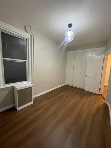 a view of an empty room with wooden floor and fan