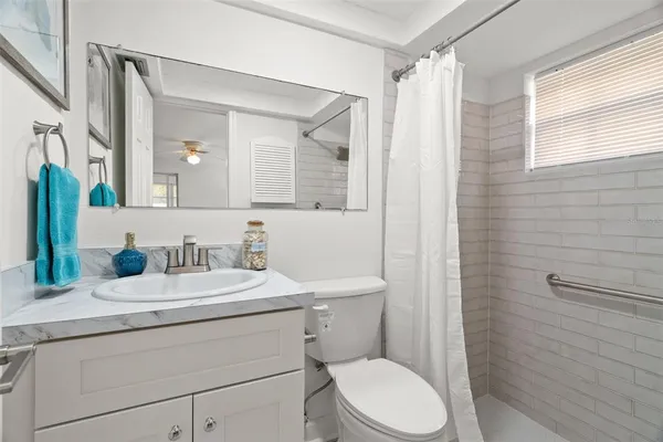 a bathroom with a granite countertop sink toilet a mirror and shower