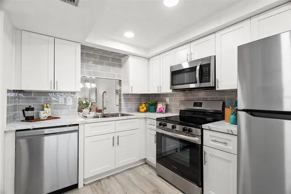 a kitchen with white cabinets white stainless steel appliances and sink