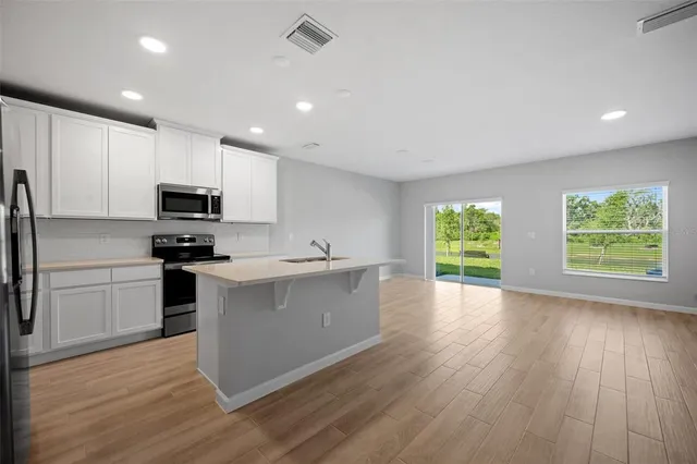 a kitchen with stainless steel appliances a stove top oven a sink dishwasher and a refrigerator with wooden floor