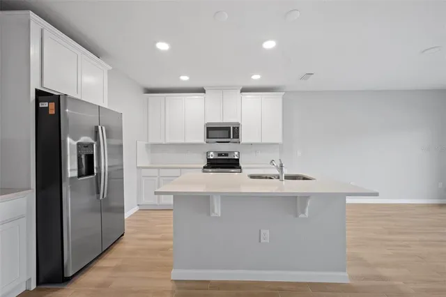 a kitchen with stainless steel appliances granite countertop a stove top oven a refrigerator and a sink