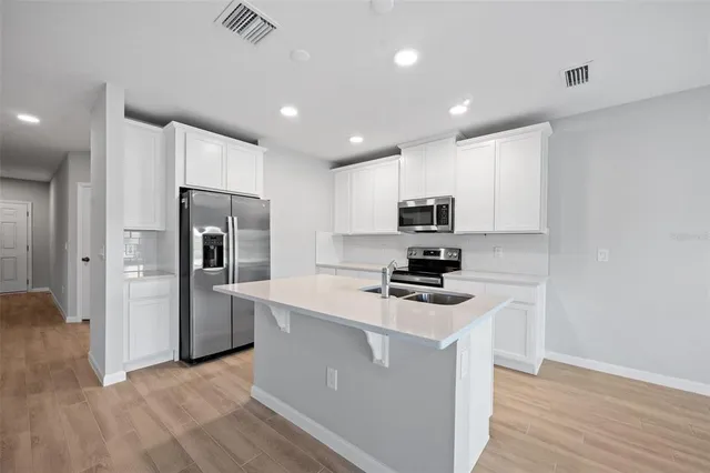 a kitchen with stainless steel appliances a refrigerator a stove a microwave and white cabinets