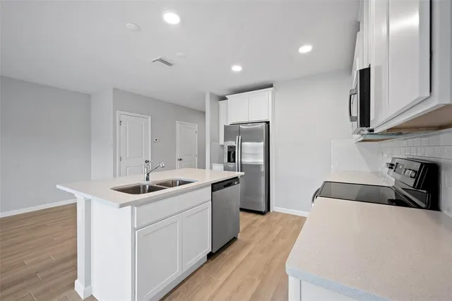 a kitchen with a sink a refrigerator and cabinets