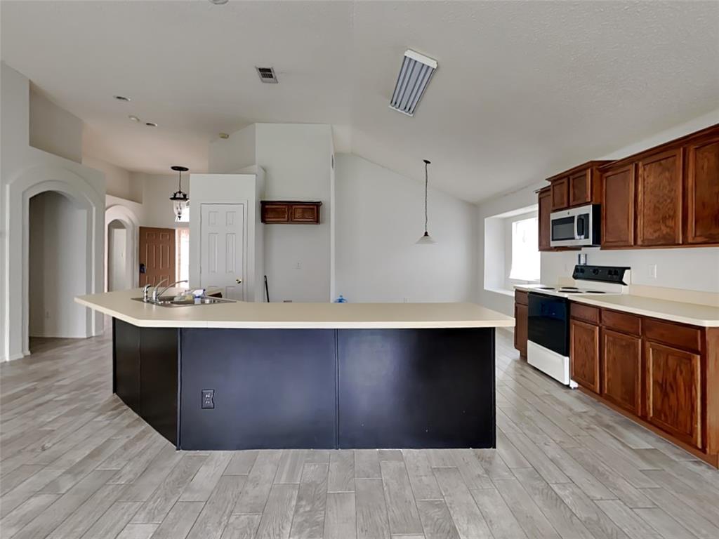 a large kitchen with wooden floor and stainless steel appliances