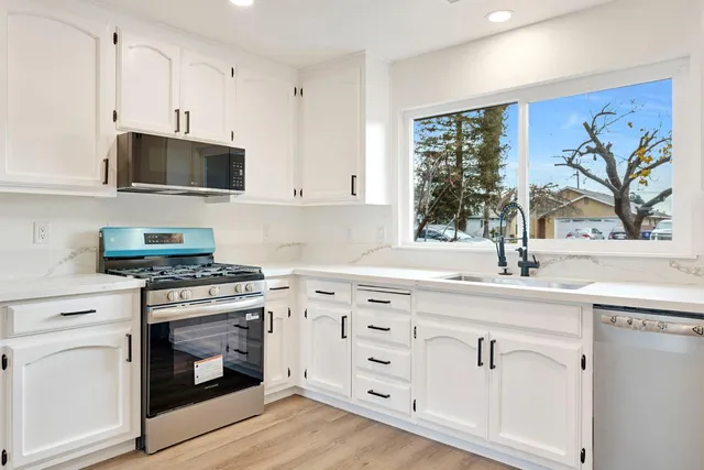 a kitchen with granite countertop a stove a sink and a microwave
