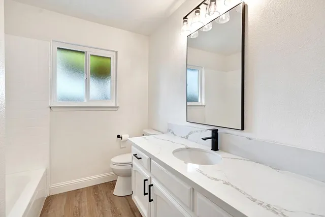 a bathroom with a granite countertop sink toilet and mirror