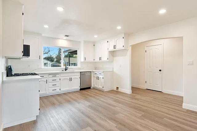a kitchen with white cabinets stainless steel appliances a sink and a window
