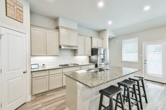 a kitchen with kitchen island granite countertop a table chairs sink and cabinets