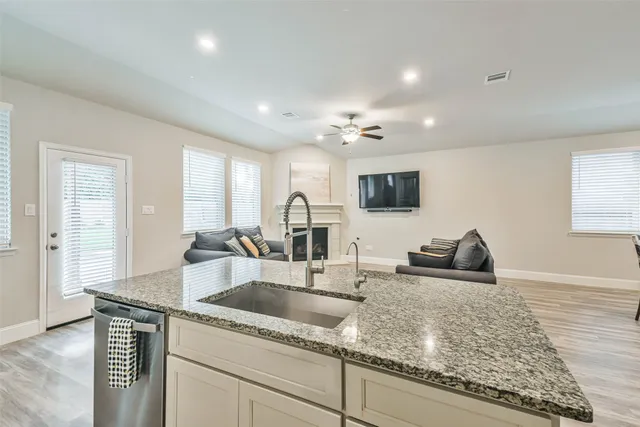 a kitchen with granite countertop a sink and a stove top oven with wooden floor