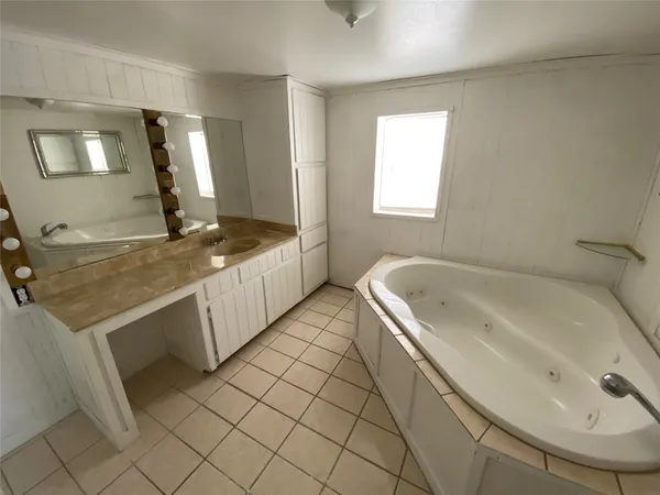 a spacious bathroom with a granite countertop sink and a bathtub