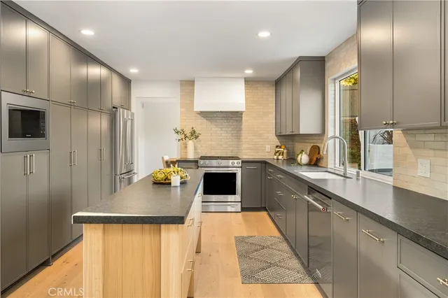 a kitchen with stainless steel appliances granite countertop a refrigerator a stove and a sink