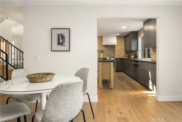 a kitchen with stainless steel appliances granite countertop a stove a sink a refrigerator white cabinets and chairs