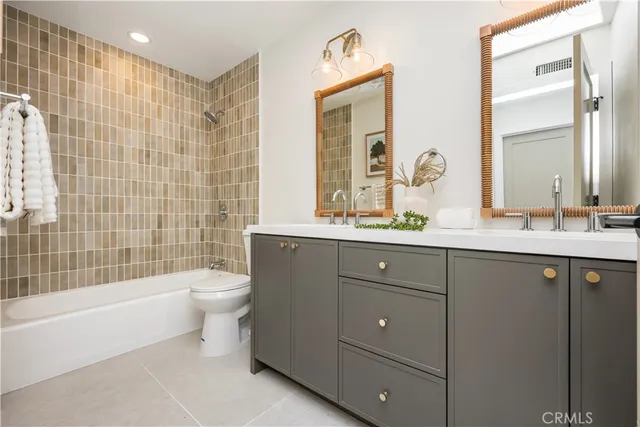 a bathroom with a double vanity sink toilet mirror and bathtub