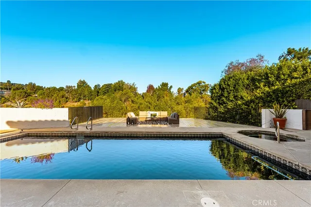 a view of swimming pool with seating area and trees in the background