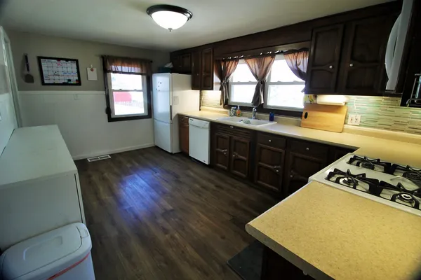 a kitchen with a wooden floor a sink a stove cabinets and a large window