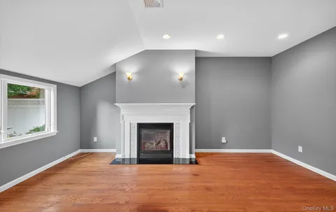 a view of empty room with wooden floor and fireplace