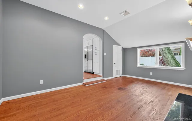 a view of an empty room with wooden floor and window