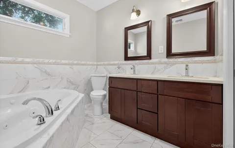 a bathroom with a double vanity sink mirror and bathtub