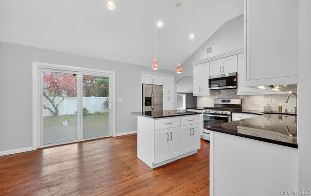 a kitchen with stainless steel appliances a stove top oven a sink a refrigerator a window