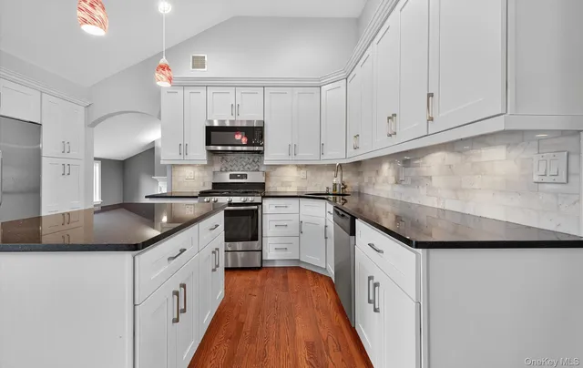 a kitchen with granite countertop a sink and dishwasher a stove top oven with white cabinets