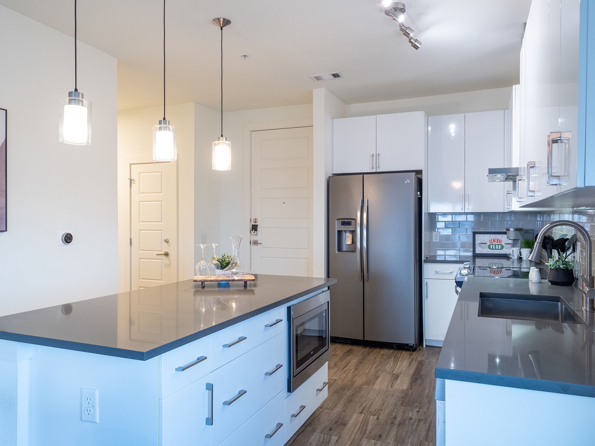 6444 Burnet Road, Unit 509 Austin, TX 78757 - Photo 4 of 32 Kitchen featuring stainless steel appliances, a center island, hanging light fixtures, white cabinetry, and dark wood-type flooring